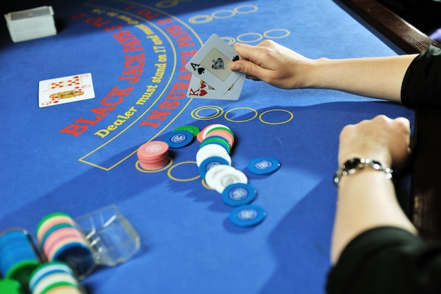 女性は青いテーブルのカジノでブラック ジャック カード ゲームをプレイします。