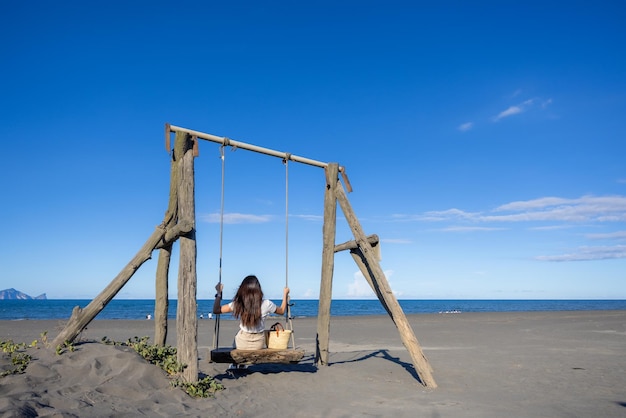 Photo woman play with swing on sand beach