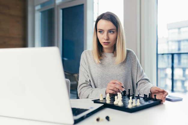 woman playing chess online uses laptop 