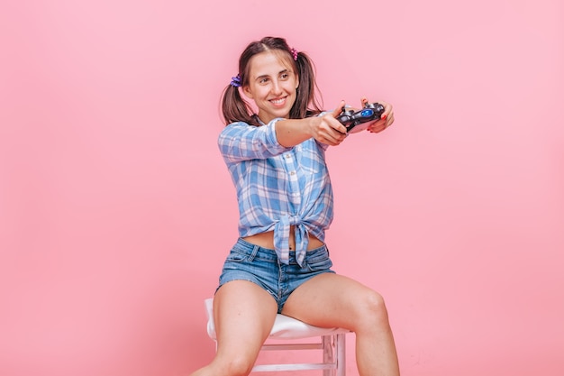 woman playing computer games with joystick on pink wall