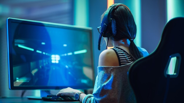 A woman playing a computer with a headset