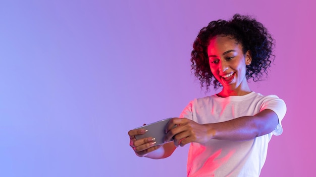 Woman playing game on smartphone in neon light