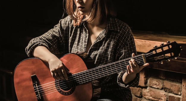 Woman playing guitar, holding an acoustic guitar in his hands.\
music concept. girl guitarist plays.