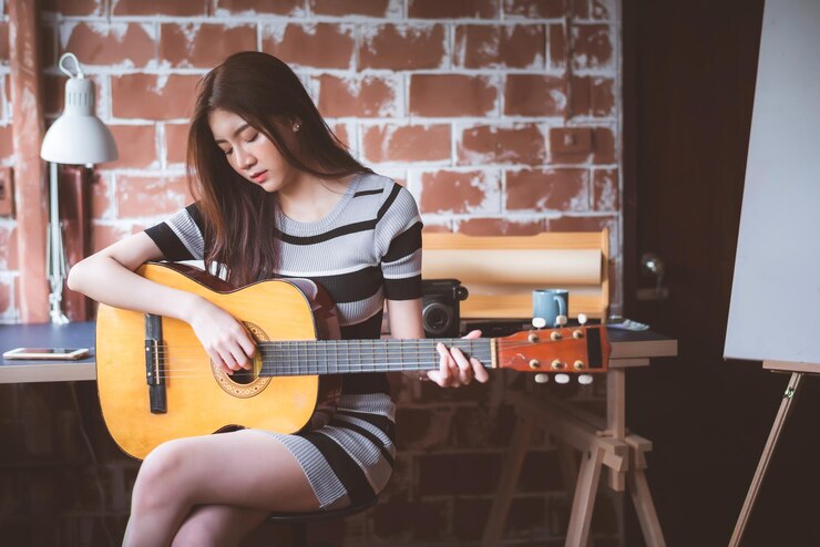 Photo 벽돌 벽 에 앉아 기타 를 연주 하는 여자