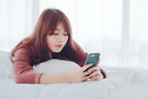 A woman playing on the phone in the bed in the house