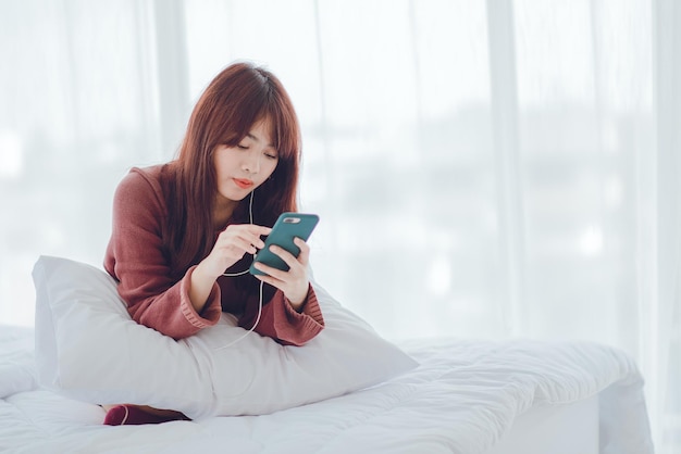 A woman playing on the phone in the bed in the house