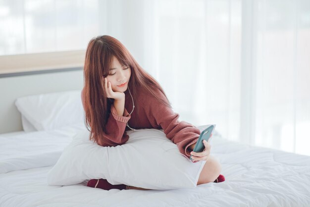 A woman playing on the phone in the bed in the house