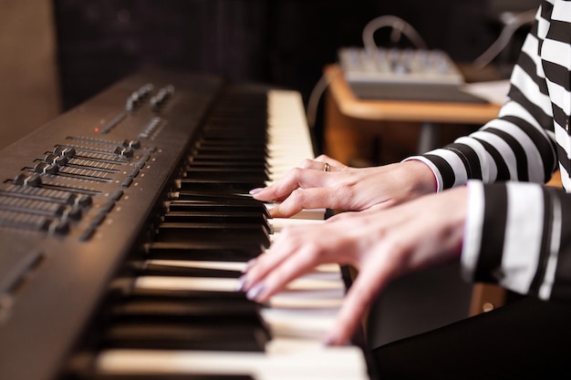 노트와 노트북을 사용하여 합성기에서 피아노 레코드 음악을 연주하는 여성 여성 손 음악가 피아니스트는 피아노 연주 기술을 향상시킵니다. 온라인 음악 교육 취미 보컬 노래 긴 웹 배너