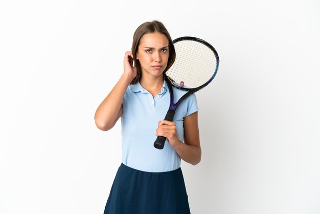 Woman playing tennis over isolated white wall having doubts