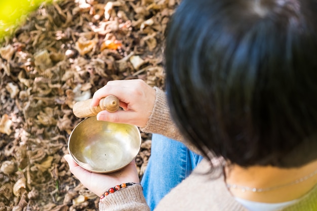 Photo woman playing on a tibetian singing bowl for sound therapy in atmosphere for healing and relax