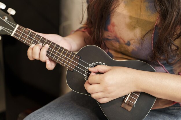 Woman playing ukulele cheerful girl learns to play at home