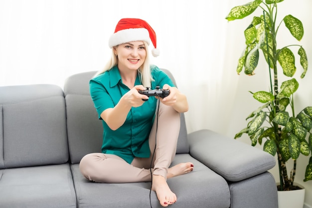 방, 새해, 크리스마스에 소파에서 비디오 게임을 하는 여자