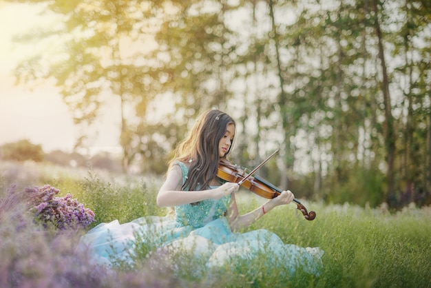 自然の花のフィールドでバイオリンを弾く女性