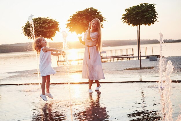 夕暮れ時の公園で海の近くの子供と遊ぶ女性