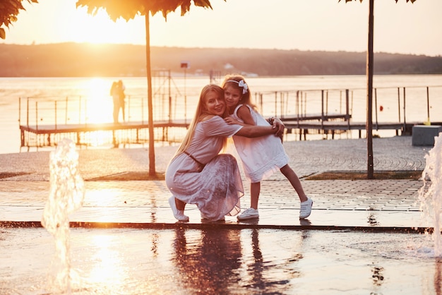 A woman playing with a child near the ocean in the park at sunset