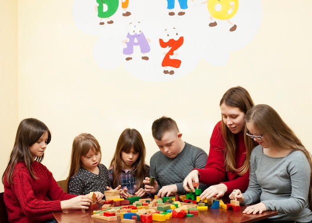 Woman playing with children with down syndrome and blocks