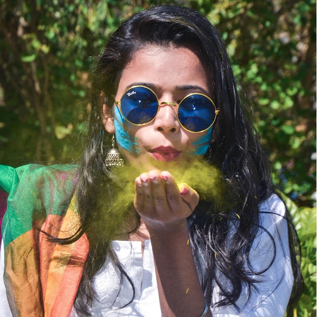 a woman playing with colours and wearing blue glasses