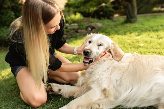 写真 緑豊かな公園で犬のラブラドールと遊ぶ女性