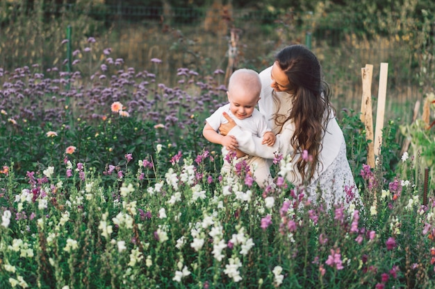 花のある温室で子供と遊ぶ女性。