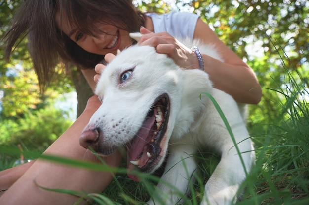 喜びから舌を保持している彼女の幸せな犬と遊ぶ女性