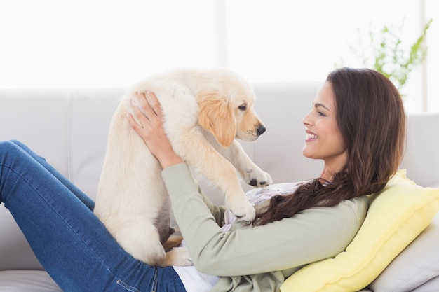 Woman playing with puppy on sofa