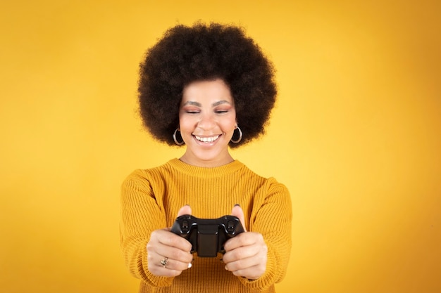 Woman playing with video game console controller, yellow\
background