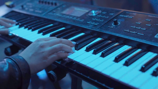 Woman plays by hands on white digital piano closeup
