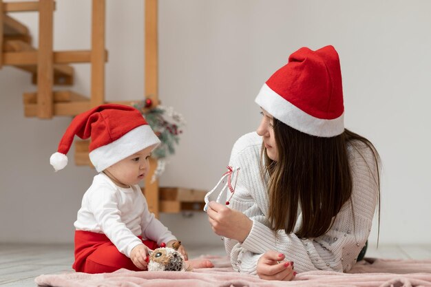 Woman plays with daughter lying on blanket laid out on floor, offers here to pick up New Year's