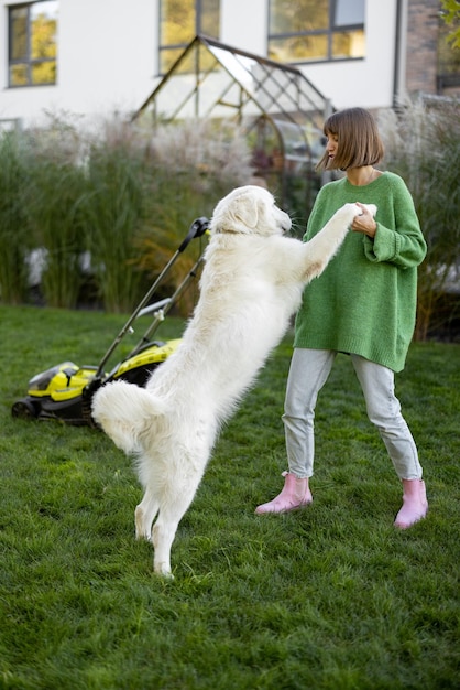 Woman plays with her dog at backyard while gardening