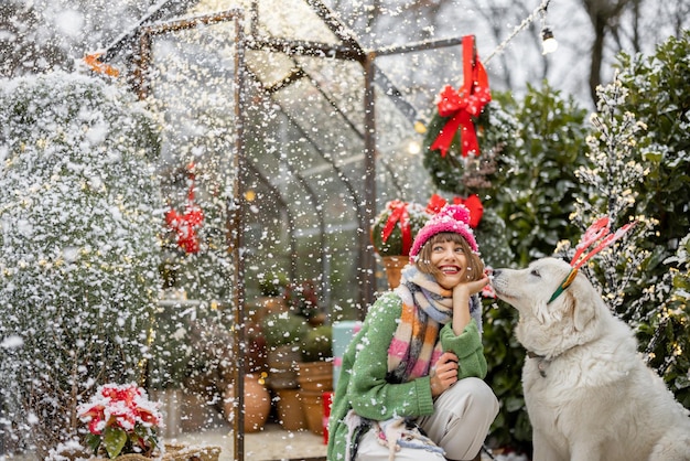 Woman plays with her dog during winter holidays at backyard