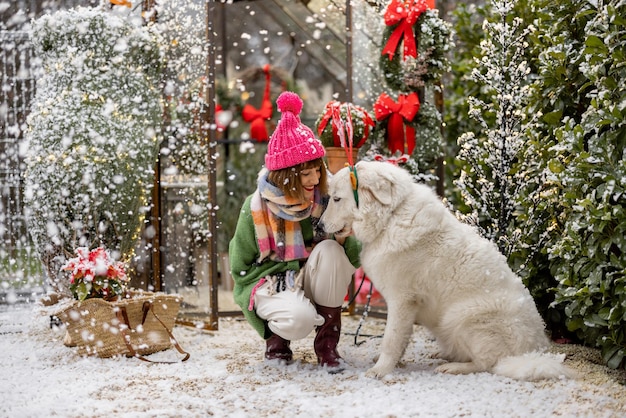 Woman plays with her dog during winter holidays at backyard