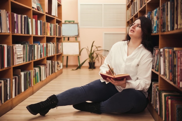 Woman of plus size American or European in library young lady with excess weight