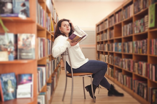 Woman of plus size American or European in library young lady with excess weight