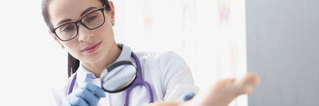 Photo woman podiatrist examining heel of patient using magnifying glass treatment of calluses and