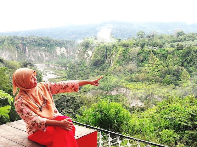 Photo woman pointing against trees and mountains