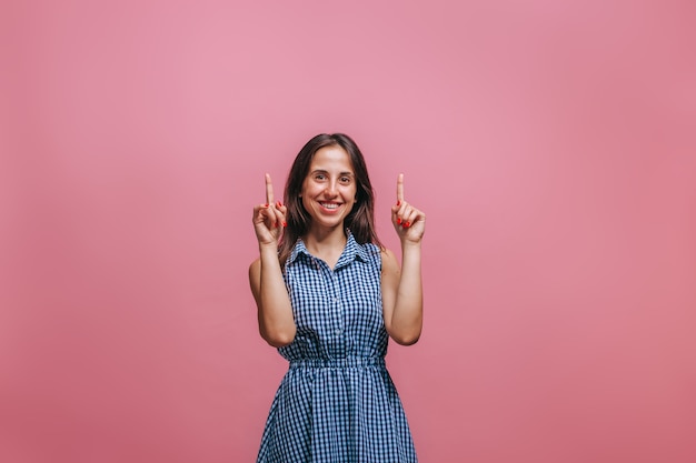 woman pointing finger up. On a pink wall