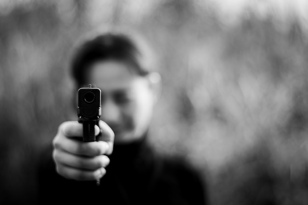 Woman pointing a gun at the target. - selective focus on front gun.