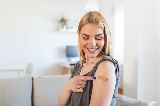 コロナウイルスワクチン接種後腕に包帯をつけて指を指している女性コロナワクチンの接種後に肩を示している若い女性