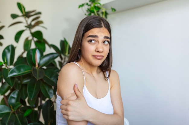 Woman pointing at his arm with a bandage after receiving the covid19 vaccine Young woman showing her shoulder after getting coronavirus vaccine