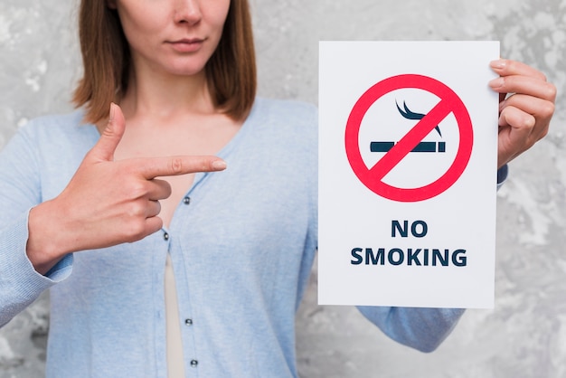 Woman pointing at paper with no smoking sign and text