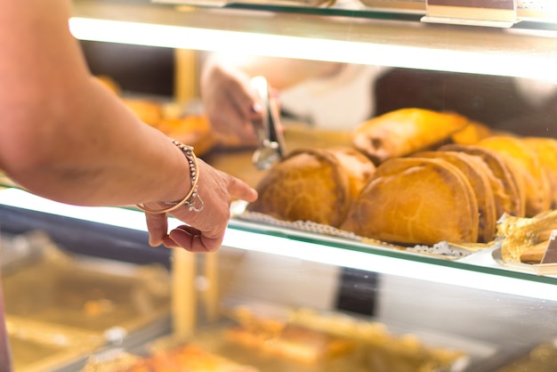 Woman pointing with a finger at a dumpling she wants to buy in a bakery