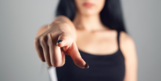 Woman points finger on gray background