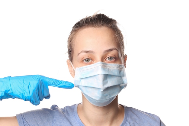 Woman points a finger at a medical mask on her face. Pandemic protection covid-19