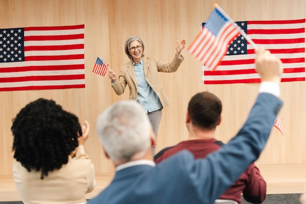 Woman politician presidential candidate holding American flag speaking with audience Vote