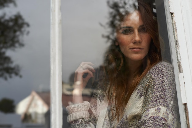 Фото Женщина портрет и расслабляется дома у окна для размышлений или внутренней мечты одинокая и таинственная молодая женщина смотрит на стекло в доме в чудесном виде или наблюдает за соседством снаружи