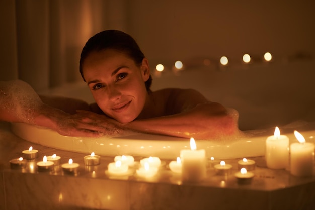 woman portrait and bath with candles or calm cleaning routine with bubbles for treatment hygiene or wellness female person face and stress relief skincare with spa peace self care or apartment