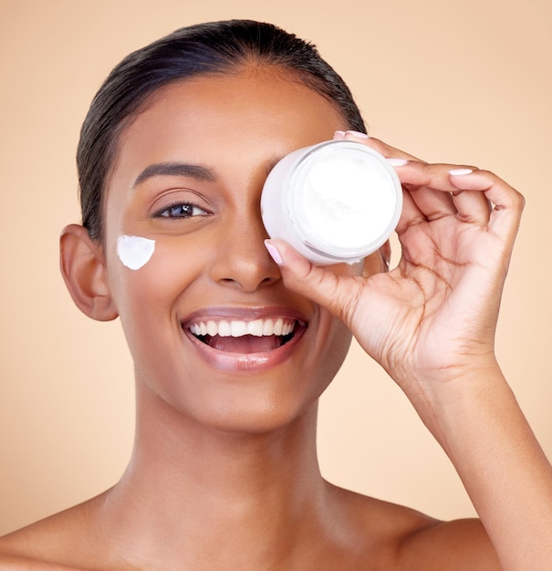 Woman portrait and cream container of eye skincare dermatology and cosmetics or self care Facial product happy face and young person or beauty model in skin care lotion on studio brown background