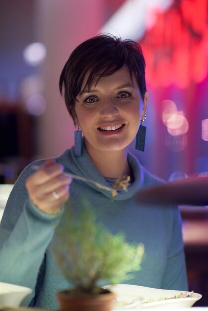 Woman portrait eating tasty dinner in modern restaurant at night