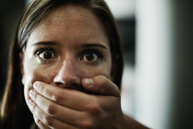 Woman portrait and hand for hostage or scared victim for danger crime or terror anxiety terrified or stalking Female person mouth and fingers of criminal in America or panic fear or kidnapping