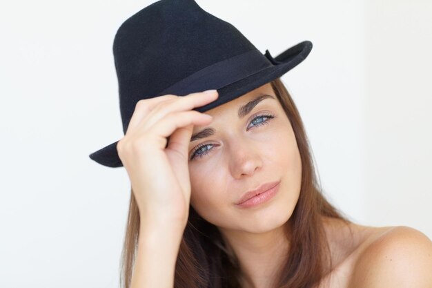 Foto ritratto di donna e cappello per la bellezza della moda o lo stile cool isolato contro uno sfondo bianco di studio il viso di una giovane donna attraente o di una modella con occhi blu e un cappello elegante sul mockup